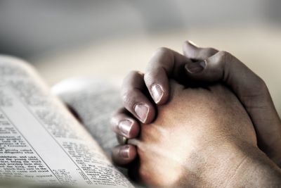 praying hands on the Bible